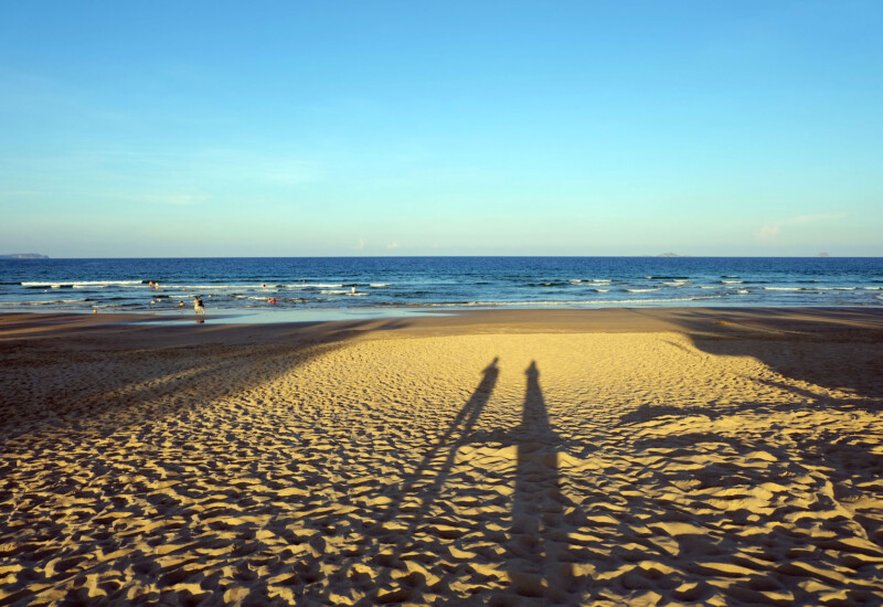 海外ビーチの砂浜にうつる夫婦ふたりの影