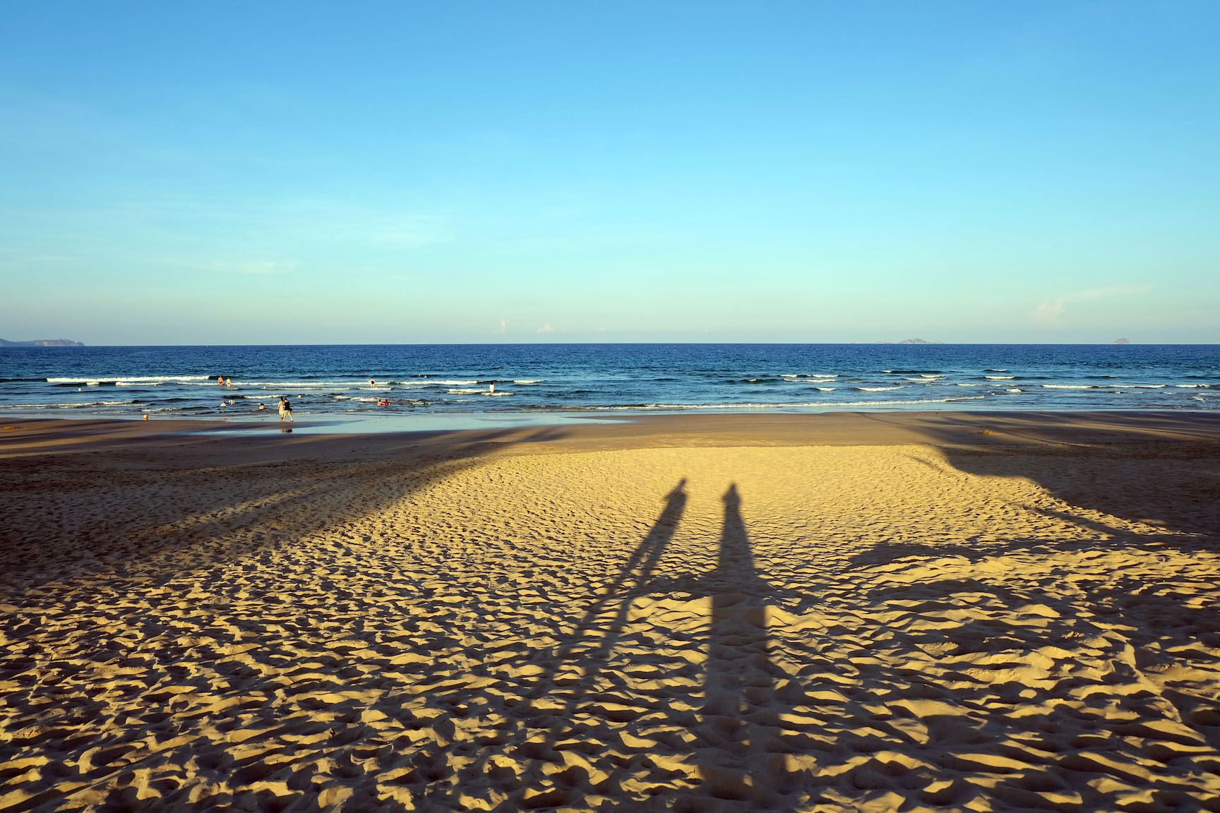 海外ビーチの砂浜にうつる夫婦ふたりの影